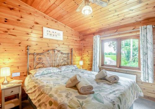 ein Schlafzimmer mit einem Bett in einer Holzhütte in der Unterkunft Search Light Meadow in Burgh