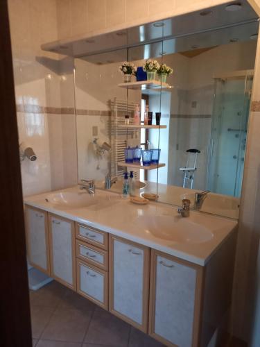 a bathroom with two sinks and a large mirror at Les Quatre Saisons in Saint-Angeau