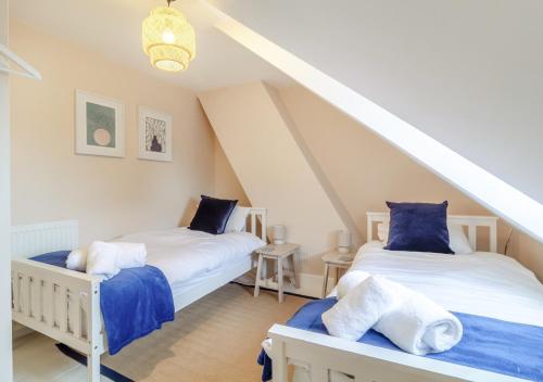 two beds in a attic room with a staircase at Seascape Cottage in Reydon