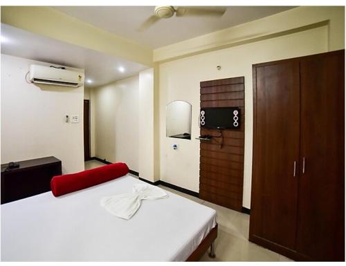 a bedroom with a white bed and a brown cabinet at Hotel Beena Mansion, Darbhanga in Darbhanga