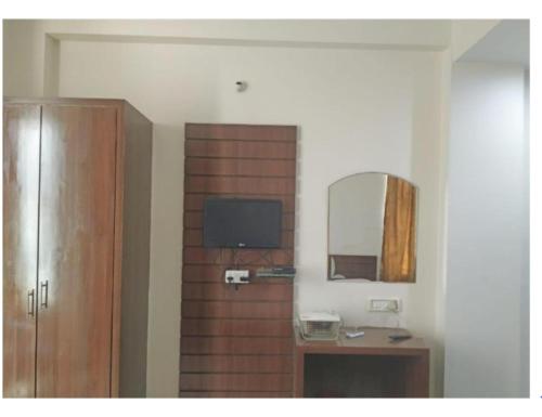 a room with a wooden wall with a mirror and a television at Hotel Beena Mansion, Darbhanga in Darbhanga