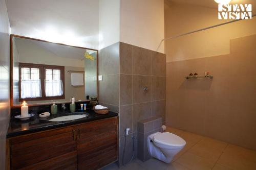 a bathroom with a toilet and a sink and a mirror at StayVista at Mikkie House 3BHK Villa Combination of Bricks & Stone - Breakfast Included in Aivarkhandpur