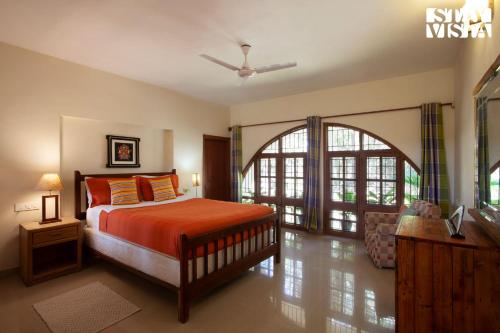 ein Schlafzimmer mit einem Bett mit orangefarbener Bettwäsche und einem Fenster in der Unterkunft StayVista at Mikkie House 3 Bedroom Villa in Aivarkhandpur