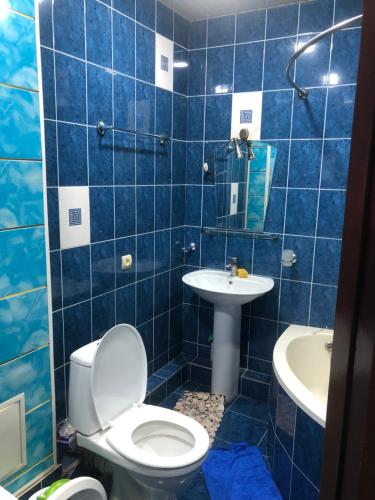 uma casa de banho em azulejos azuis com um WC e um lavatório em Айбек 20 em Yakkasaray