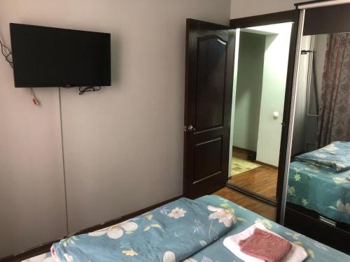 um quarto com uma televisão, uma cama e um espelho em Айбек 20 em Yakkasaray