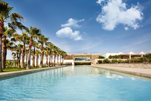 a swimming pool with palm trees in front of a building at Two Rooms Hotel in Urla