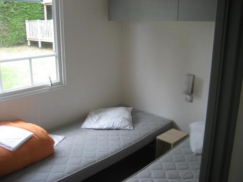 Cette petite chambre comprend un lit et une fenêtre. dans l'établissement Camping le Rochat Belle Isle, à Châteauroux