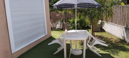 una mesa y una silla bajo una sombrilla en un patio en Vacances à la mer., en Six-Fours-les-Plages