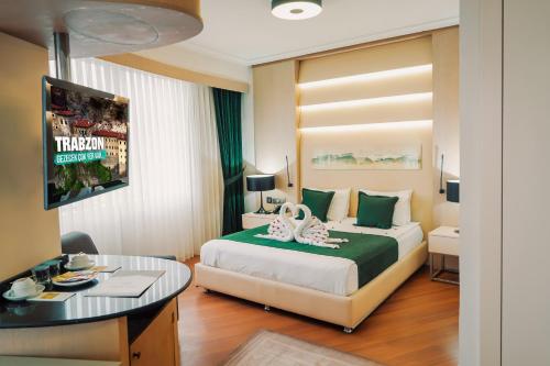 トラブゾンにあるKONAK PARK HOTELのベッドとテーブルが備わるホテルルームです。