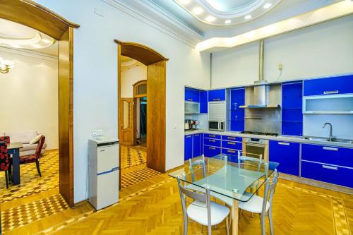 eine Küche mit blauen Schränken und einem Glastisch in der Unterkunft Big Apartment Saray in Baku