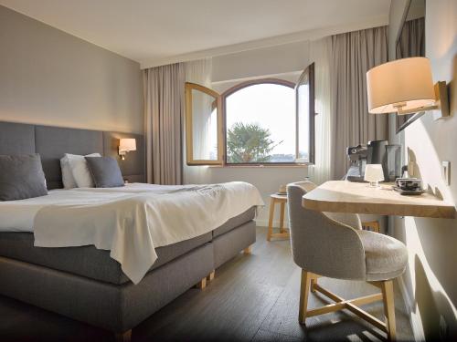 フーレンにあるHotel De Kommelのベッド、テーブル、椅子が備わるホテルルームです。