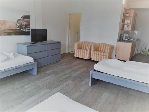 a room with two beds and a tv and two chairs at Mehrbett-Apartment 8 Citynah, einfache Ausstattung in Hamburg