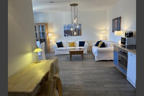 a living room with white couches and a kitchen at Ferienwohnung Landhaus 44 Citynah, toskanischer Flair in Hamburg