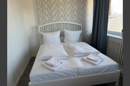 Una cama blanca con toallas y una ventana. en Ferienwohnung Landhaus 44 Citynah, toskanischer Flair, en Hamburgo