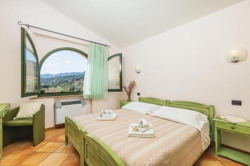 a bedroom with a bed and a large window at Hotel Janas in Tertenìa