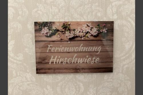 a sign on a wooden wall with flowers on it at Studio- Apartment Hirschwiese 52 "cozy" für zwei in Hamburg