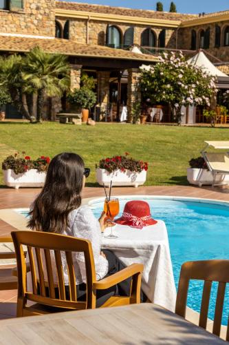 a woman sitting at a table next to a pool at Hotel Janas in Tertenìa