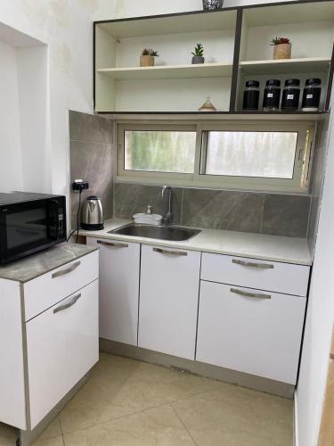 a kitchen with white cabinets and a sink and a microwave at בקתת אברהם in Safed