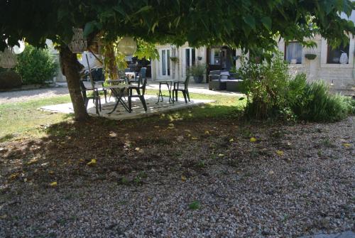 a table and chairs under a tree in front of a house at hOTEL kARINA in Jarnac