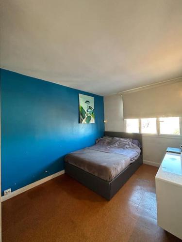 une chambre avec un mur bleu et un lit dans l'établissement Appartement familial (idéal JO 2024), à Montreuil