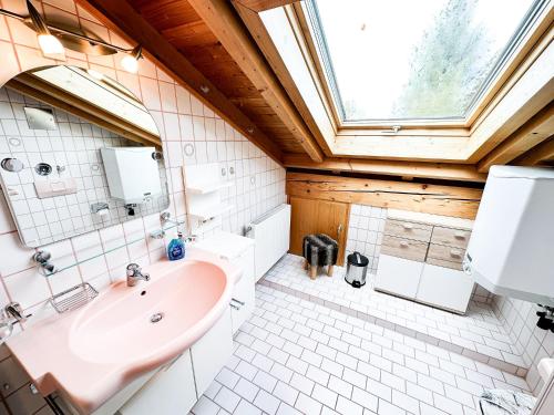 een badkamer met een roze wastafel en een raam bij FeWo "Sonnenschein" Oberreute in Oberreute