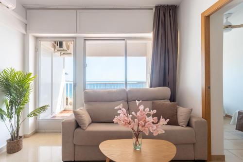 a living room with a couch and a table with flowers at Apartamentos Mirador in Benidorm