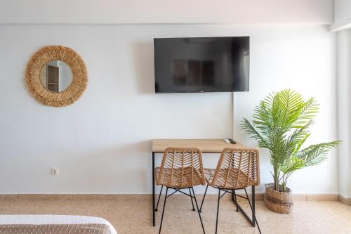 a table with two chairs and a tv on a wall at Apartamentos Mirador in Benidorm