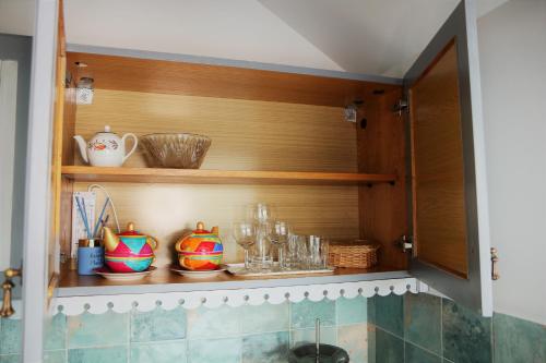 a kitchen with wooden shelves with glasses and dishes at Studio apartment in Jeruzalė in Vilnius