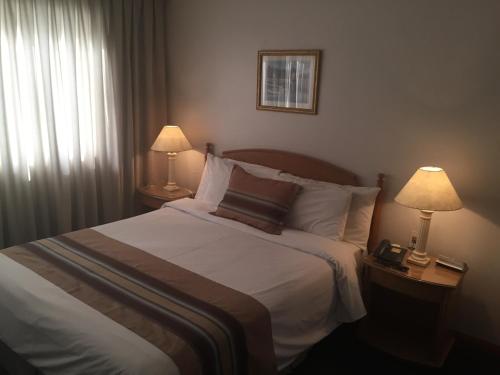 a bedroom with a large bed with two lamps on tables at Crystal Palace Hotel in Montevideo
