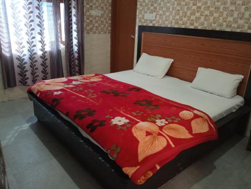 a bed with a red blanket with flowers on it at Shri mad bhagavat mandir in Vrindāvan