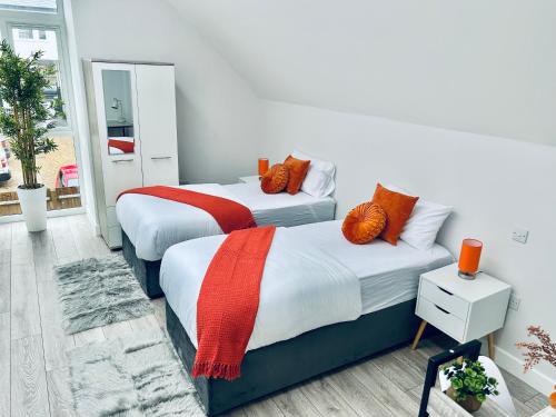 2 bedden met oranje kussens in een kamer bij Luxury Town Centre House, Faversham in Faversham