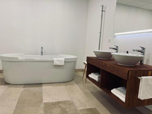 a bathroom with two sinks and a bath tub at Château Lecusse - La Grande Roche - Hôtel, Spa, Boutique & Restaurant in Broze
