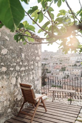 a chair sitting on a wooden deck with a view of a city at CASA TALIA - Rooms in Modica