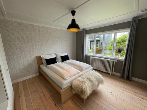 a bedroom with a bed with a furry pillow and a window at Cozy Apartment downtown Tórshavn in Tórshavn