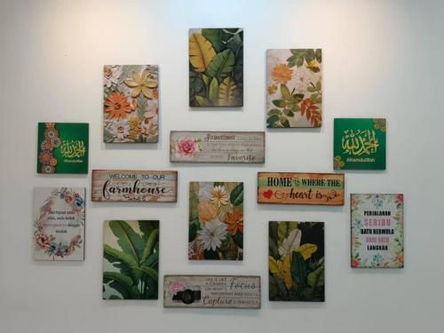 a wall with pictures of flowers and books on it at Rabb Homestay Samarahan in Kampong Setigang