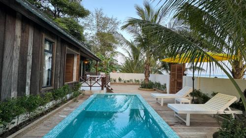 a swimming pool with two chairs and a house at One Beach Private Villa in Phumĭ Kaôh Rŭng Sâmlœ̆m Khnŏng