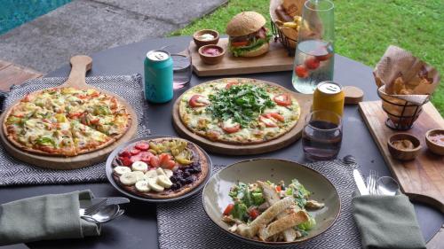 a table with three pizzas and other food on it at Origin Ubud in Ubud