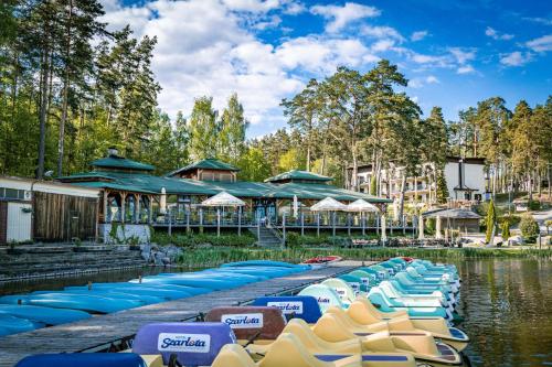 eine Reihe von Stühlen und Sonnenschirmen auf dem Wasser in einem Resort in der Unterkunft Domki Szarlota - atrakcje dla rodzin na Kaszubach in Kościerzyna