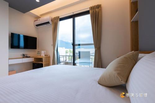 1 dormitorio con 1 cama grande y ventana grande en 聚一夏民宿, en Jiali