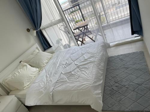 ein weißes Bett in einem Zimmer mit Fenster in der Unterkunft The Bridges Abu Dhabi Holiday Homes in Abu Dhabi