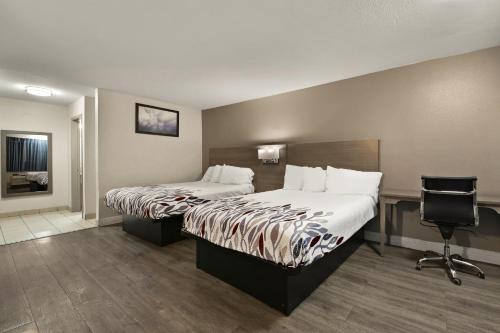 a hotel room with two beds and a chair at Red Roof Inn Los Angeles - Bellflower in Bellflower