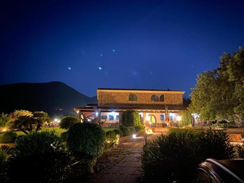 a large building with lights in a yard at night at Hotel Janas in Tertenìa