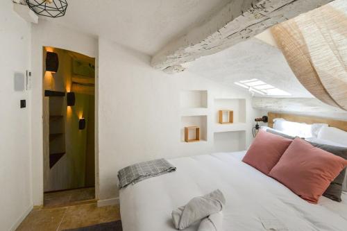 a bedroom with a white bed with pink pillows at Superbe appartement Saint Paul de Vence 4P in Saint Paul de Vence