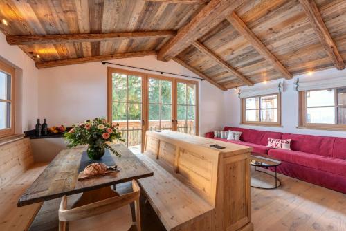 a living room with a red couch and a wooden table at Chalet Marmotta CULM - Luxus Chalet Ski-In Ski-Out in Sankt Anton am Arlberg