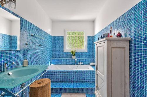 La salle de bains est pourvue de carrelage bleu, d'une baignoire et d'un lavabo. dans l'établissement 10mn de Cannes, villa entière de 150m2., au Cannet