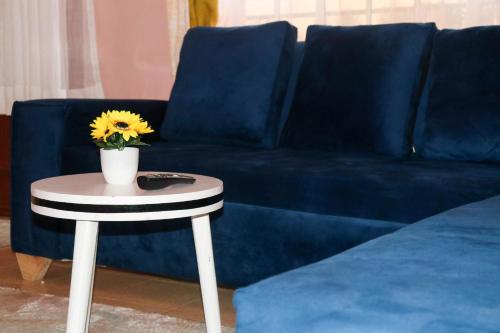 Un sofá azul con una mesa con un girasol. en Trendy Homes - 2 Bedroom, en Bungoma
