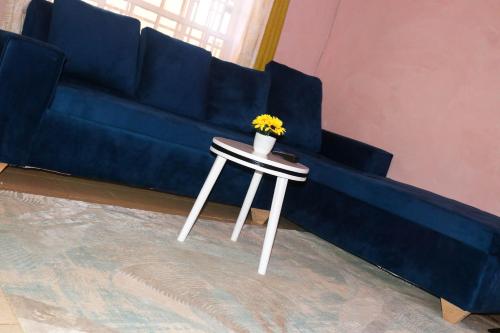 Un sofá azul con una mesa con una planta. en Trendy Homes - 2 Bedroom, en Bungoma
