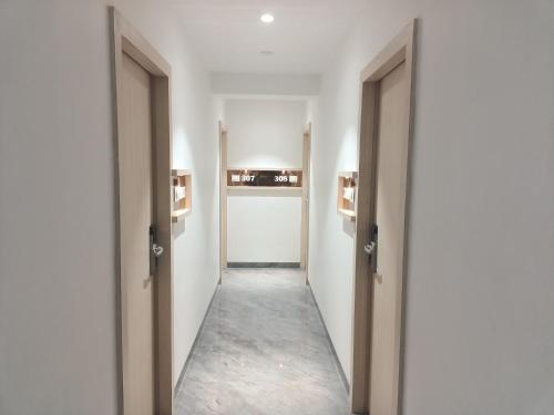 an empty corridor with two open doors and a hallway with a hallway at Hotel Pearl Residency Thane in Thane