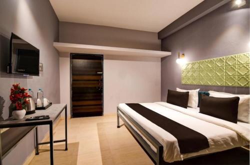a bedroom with a bed and a desk and a television at HOTEL NEATFLIX & CHILL 2 in Bhubaneshwar