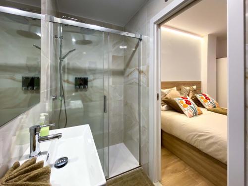 a bathroom with a shower and a sink and a bed at Refugio 2BR y 2BA Azca/Bernabéu in Madrid